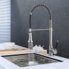 Modern stainless steel kitchen faucet with pull-down sprayer and coiled hose actively dispensing water into sink
