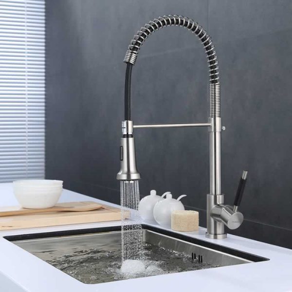 Modern stainless steel kitchen faucet with pull-down sprayer and coiled hose actively dispensing water into sink