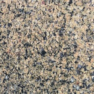 Polished granite countertop surface with beige, tan, and dark black speckles throughout