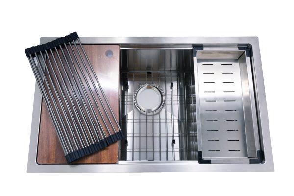 Stainless steel kitchen sink with multiple compartments including cutting board, colander, and strainer basket with accessories