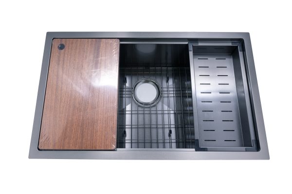 Stainless steel kitchen sink with wooden cutting board, metal grid, and black strainer accessories