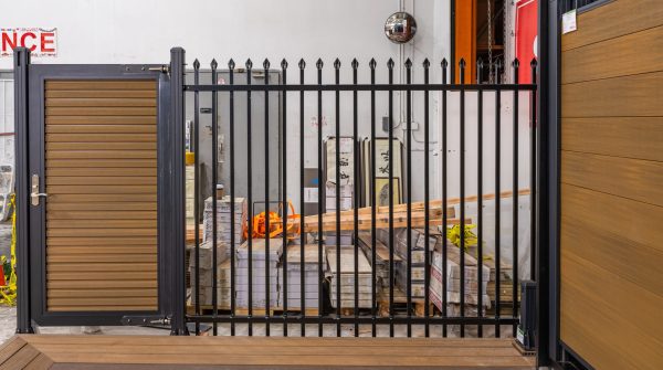 Black metal vertical bar fence gate with spear points installed in front of wooden garage doors at a residential property