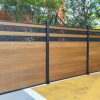 Multi-panel privacy fence with horizontal wood composite boards and dark metal posts with decorative metal inserts