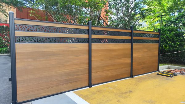 Multi-panel privacy fence with horizontal wood composite boards and dark metal posts with decorative metal inserts