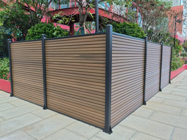Outdoor privacy screen fence with horizontal wood composite slats and dark metal posts in urban garden setting