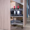 Modern kitchen island detail showing open cabinet with HIGOLD coffee machine, red candles, and wooden accessories inside