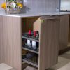 Modern kitchen island with light wood cabinetry, white countertop, built-in coffee machine with red candles and decorative flower basket