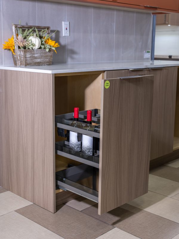 Modern kitchen island with light wood cabinetry, white countertop, built-in coffee machine with red candles and decorative flower basket