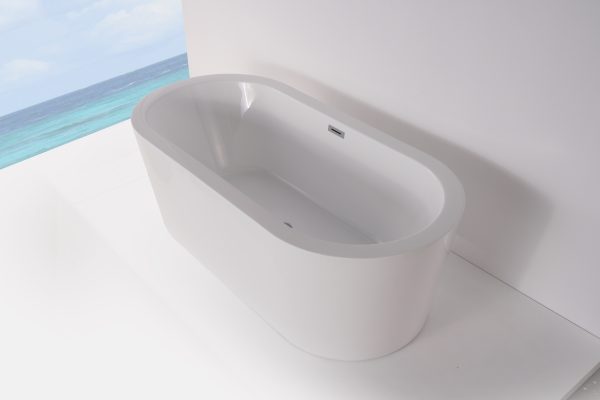 Close-up of white freestanding soaking tub with overflow drain next to ocean view window