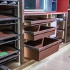 Angled view of closet interior showing extended brown drawers, open shelving with organized items, and mirrored doors on right side with warm LED lighting