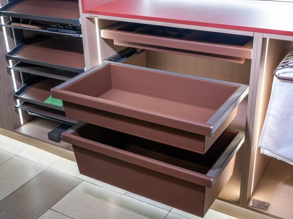 Close-up view of pull-out brown drawers in a closet system with one drawer extended showing interior storage capacity