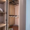 Walk-in closet interior showing brown pull-out drawers, metal hanging rod with black hangers, and multiple shelves with accent lighting