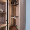 Modern closet organizer with pull-out brown drawers, black hangers on rod, and shelving system with LED lighting