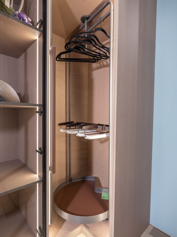 Modern closet organizer with pull-out brown drawers, black hangers on rod, and shelving system with LED lighting
