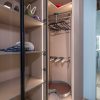 Open walk-in closet displaying hanging rod with black hangers, white item on shelf, and brown storage container