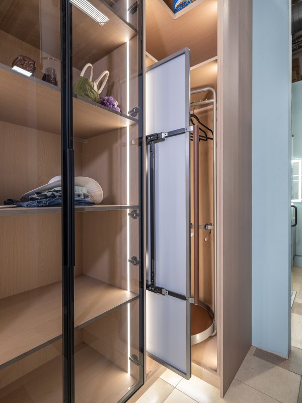 Walk-in closet interior showing white frosted glass sliding doors and organized wooden shelves with lighting