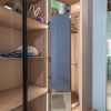 Modern walk-in closet with glass doors, wooden shelving, ambient lighting, and blue storage box