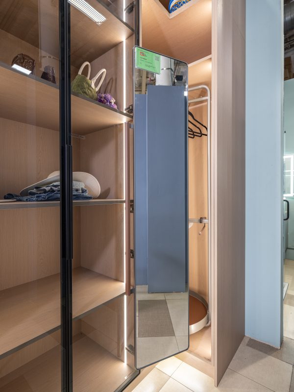 Modern walk-in closet with glass doors, wooden shelving, ambient lighting, and blue storage box