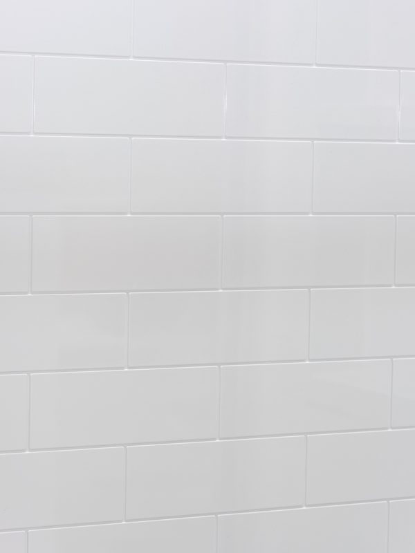Angled view of white subway tile backsplash with subtle grout lines in staggered brick layout