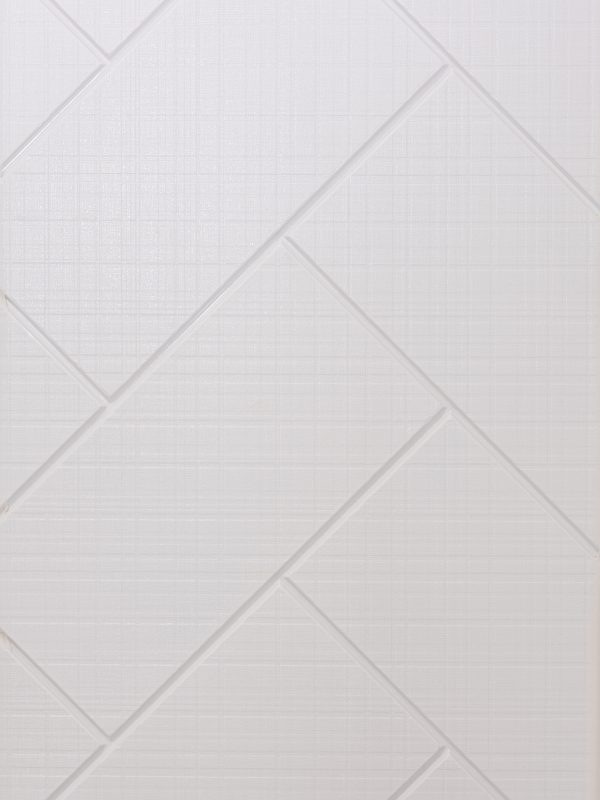 Close-up of white subway tiles arranged in large-scale herringbone pattern with subtle beveled edges