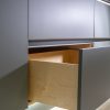 Partially open wooden drawer displaying light natural wood construction with metal rail handle