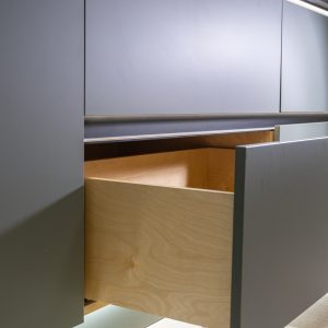 Partially open wooden drawer displaying light natural wood construction with metal rail handle
