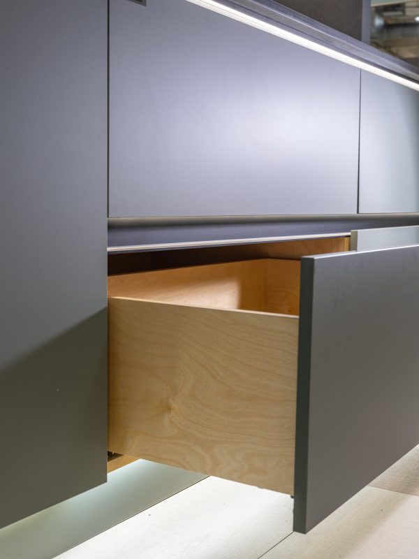 Partially open wooden drawer displaying light natural wood construction with metal rail handle
