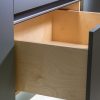 Open wooden drawer with light wood interior and metal handle in modern cabinetry