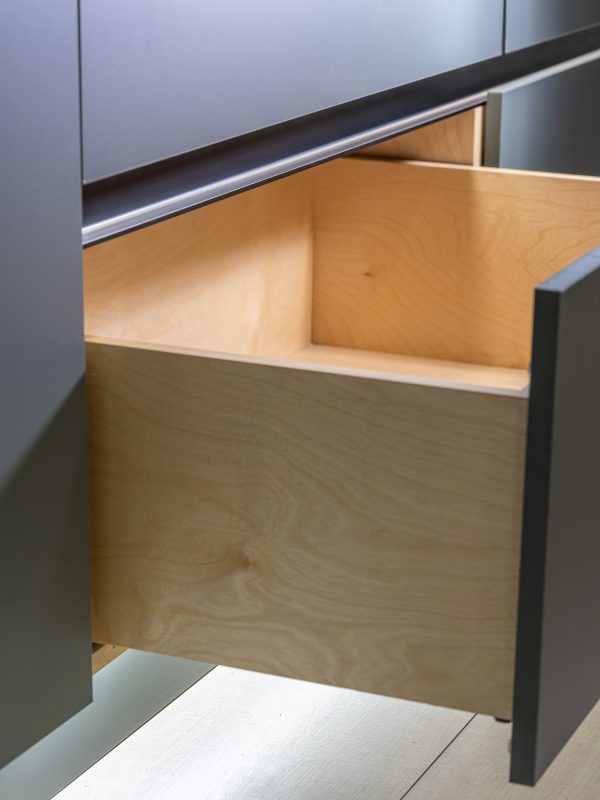 Open wooden drawer with light wood interior and metal handle in modern cabinetry