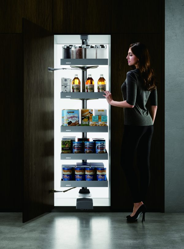 Woman opening a tall pull-out rotating pantry cabinet with five shelves stocked with canned goods and beverages