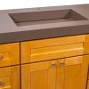 Close-up detail of brown bathroom countertop sink basin with sloped sides on golden oak vanity cabinet