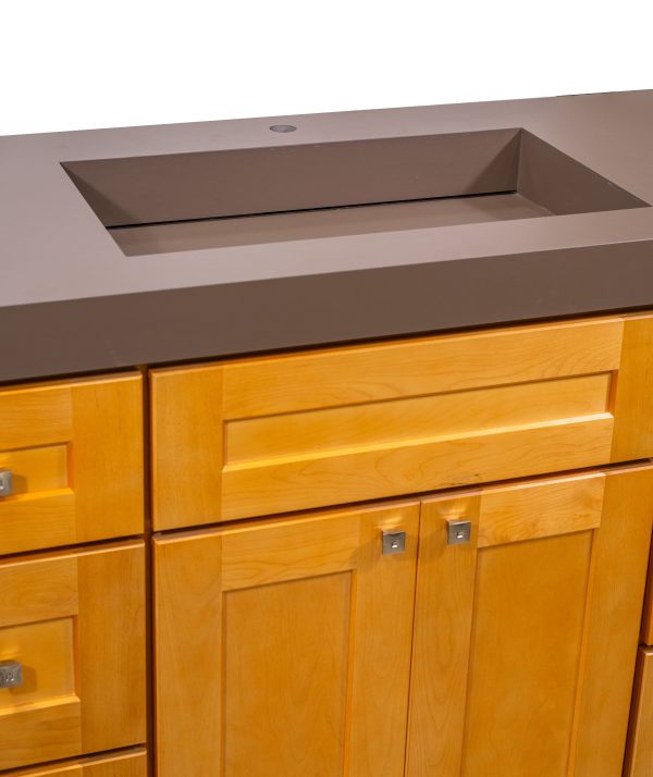 Close-up detail of brown bathroom countertop sink basin with sloped sides on golden oak vanity cabinet