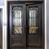 Black double doors with ornate wrought iron scrollwork and decorative glass panels featuring geometric patterns and gold accents