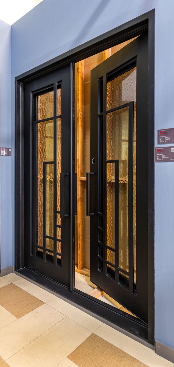 Black double doors with 8-pane grid windows and golden textured glass panels, illuminated from interior with warm lighting
