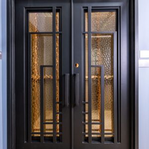 Black double doors with 4-pane windows featuring golden hammered glass panels and horizontal metal muntins