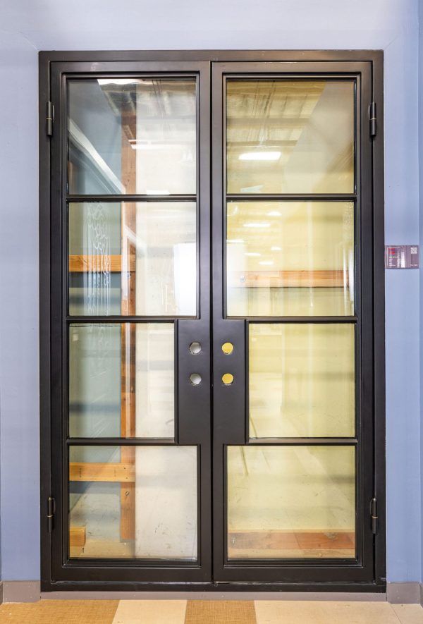 Black double doors with 4 glass panes per door and dual gold knobs in closed position