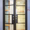 Black double doors with 4-pane glass panels each and gold door handles, partially open position
