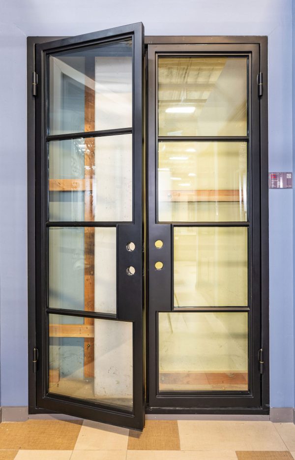 Black double doors with 4-pane glass panels each and gold door handles, partially open position