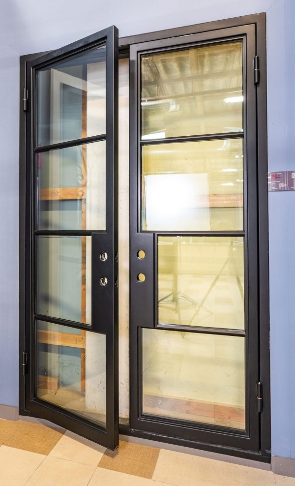 Black framed double doors with clear glass panes and gold hardware, one door open showing interior