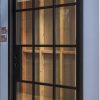 Black-framed modern sliding glass door with 12-pane grid pattern and wooden interior visible through glass panels