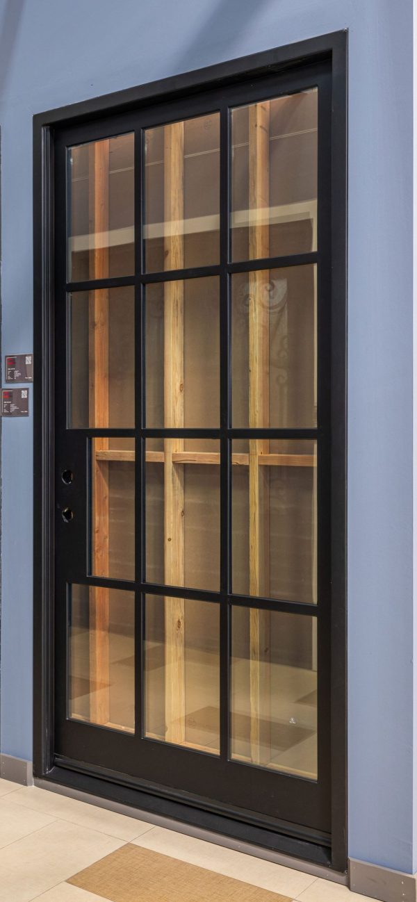 Black-framed modern sliding glass door with 12-pane grid pattern and wooden interior visible through glass panels