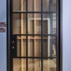 Single black door with 12-pane glass grid pattern and gold hardware in modern architectural setting