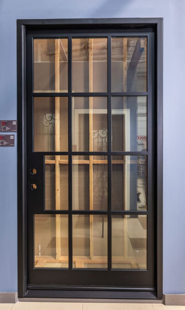 Single black door with 12-pane glass grid pattern and gold hardware in modern architectural setting