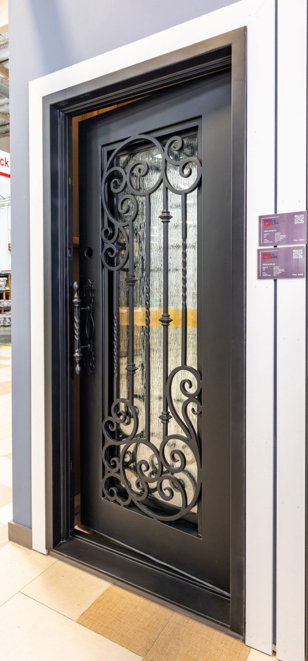 Black metal entry door with elaborate wrought iron filigree design and cream frame