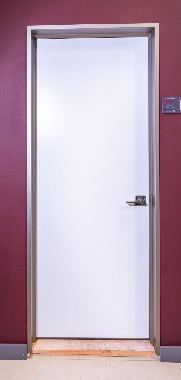 White interior door with silver metal frame and modern lever handle against burgundy wall