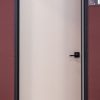Modern white interior door with black handle and dark frame against burgundy wall