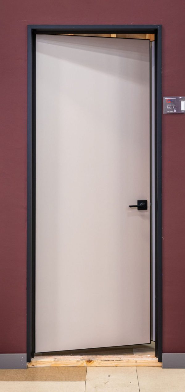 Modern white interior door with black handle and dark frame against burgundy wall