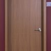 Closed wooden interior door with walnut finish and rectangular panel detail against burgundy wall