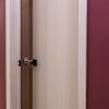 Light wood interior door frame with open door revealing dark walnut door inside, showing contrast between frame and door colors