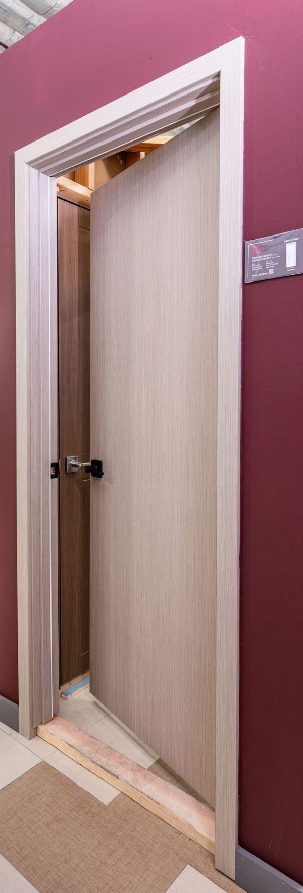Light wood interior door frame with open door revealing dark walnut door inside, showing contrast between frame and door colors